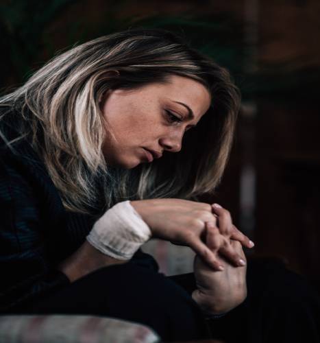 Psychotherapy office. Suicidal woman with bandaged wrist talking to psychotherapist about her problems